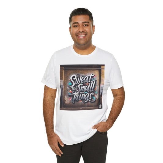 A man wearing a white Unisex ‘Sweat the Small Things’ graphic tee — bold typography shirt highlighting that small details and daily discipline create the foundation for every big achievement.